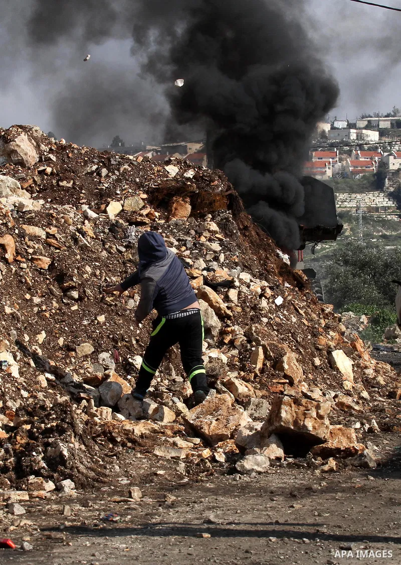 A Palestinian protester hurls stones toward Israeli security forces during clashes following a protest against the expropriation of Palestinian land by Israel in the West Bank village of Kafr Qaddum, near the northern ci...