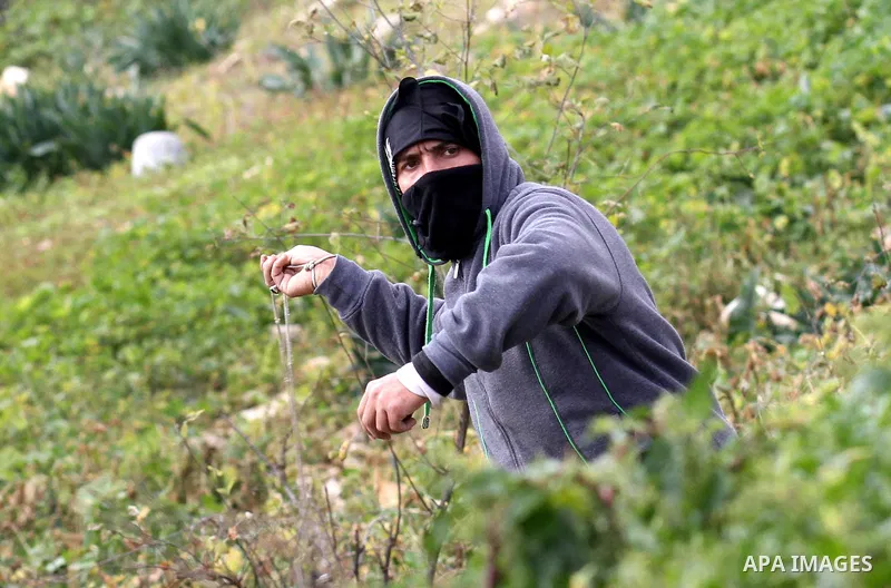 A Palestinian protester uses a slingshot to hurl stones toward Israeli security forces during clashes following a protest against the expropriation of Palestinian land by Israel in the West Bank village of Kafr Qaddum, n...
