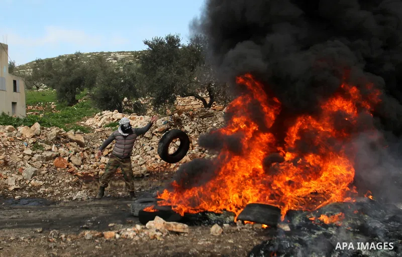 A Palestinian protester burns tires during clashes following a protest against the expropriation of Palestinian land by Israel in the West Bank village of Kafr Qaddum, near the northern city of Nablus on Jan. 29, 2016. P...
