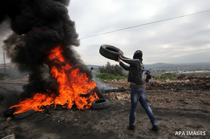 A Palestinian protester burns tires during clashes following a protest against the expropriation of Palestinian land by Israel in the West Bank village of Kafr Qaddum, near the northern city of Nablus on Jan. 29, 2016. P...