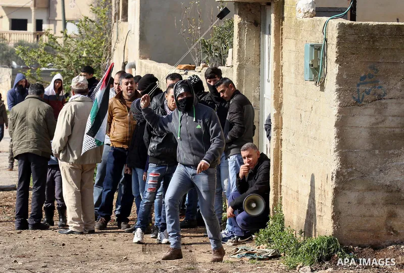 A Palestinian protester uses a slingshot to hurl stones toward Israeli security forces during clashes following a protest against the expropriation of Palestinian land by Israel in the West Bank village of Kafr Qaddum, n...