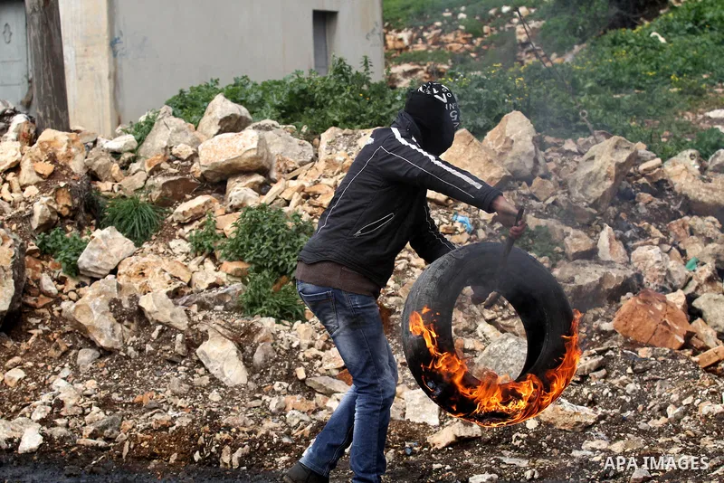 A Palestinian protester burns tires during clashes following a protest against the expropriation of Palestinian land by Israel in the West Bank village of Kafr Qaddum, near the northern city of Nablus on Jan. 29, 2016. P...