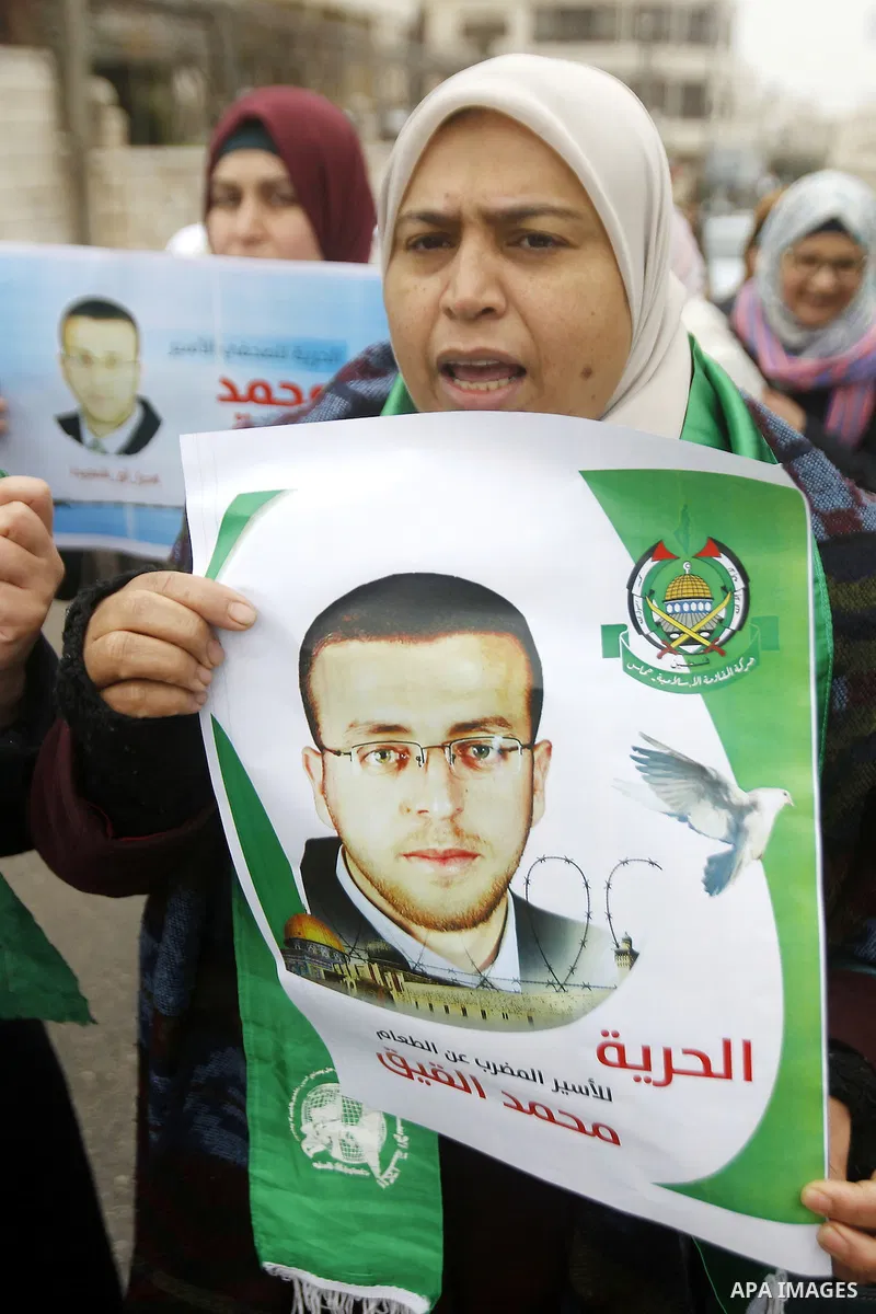 A Palestinian woman holds a poster bearing a portrait of Palestinian journalist Mohammed al-Qiq who is imprisoned in an Israeli jail during a protest in support of his hunger strike in the West Bank city of Hebron on Jan...
