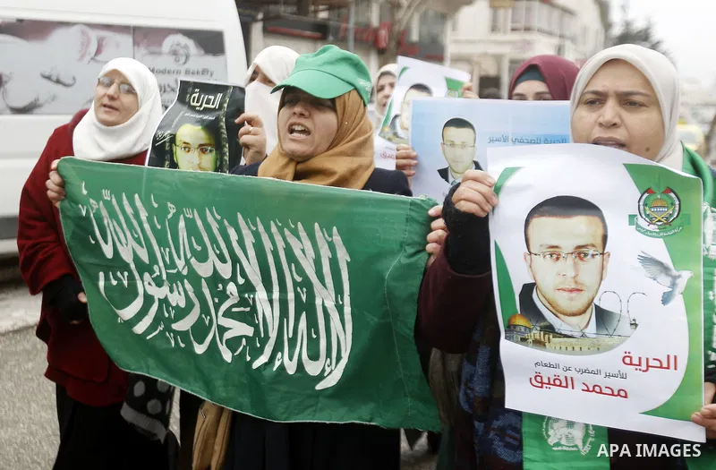 Palestinians hold posters bearing a portrait of Palestinian journalist Mohammed al-Qiq who is imprisoned in an Israeli jail during a protest in support of his hunger strike in the West Bank city of Hebron on January 29,...