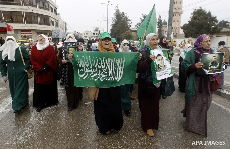 Palestinians hold posters bearing a portrait of Palestinian journalist Mohammed al-Qiq who is imprisoned in an Israeli jail during a protest in support of his hunger strike in the West Bank city of Hebron on January 29,...