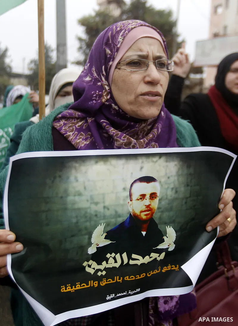 A Palestinian woman holds a poster bearing a portrait of Palestinian journalist Mohammed al-Qiq who is imprisoned in an Israeli jail during a protest in support of his hunger strike in the West Bank city of Hebron on Jan...