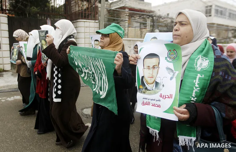 Palestinians hold posters bearing a portrait of Palestinian journalist Mohammed al-Qiq who is imprisoned in an Israeli jail during a protest in support of his hunger strike in the West Bank city of Hebron on January 29,...