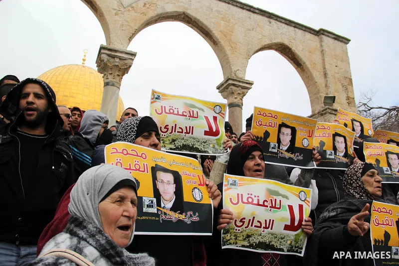 Palestinians hold posters bearing a portrait of Palestinian journalist Mohammed al-Qiq who is imprisoned in an Israeli jail during a protest in support of his hunger strike in front of Jerusalem's Dome of the Rock mosque...