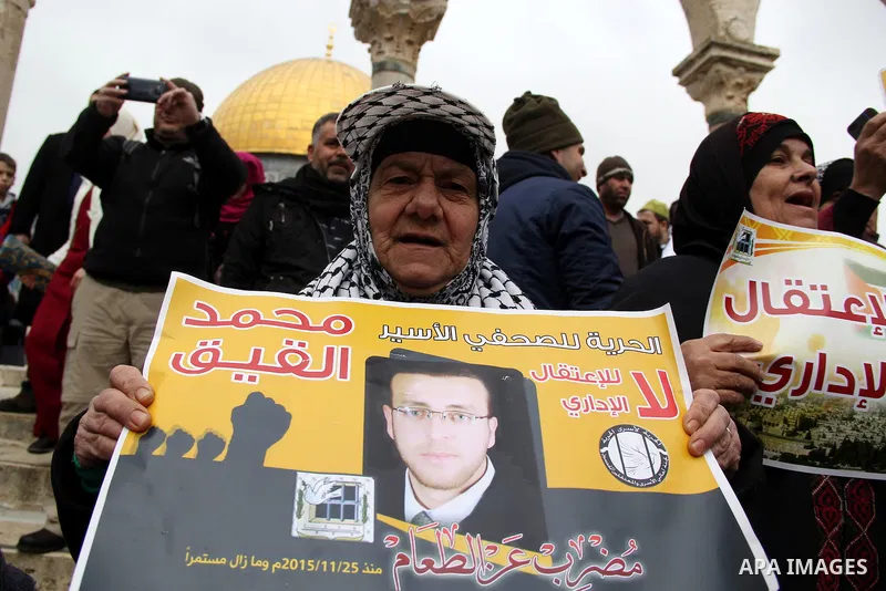 Palestinians hold posters bearing a portrait of Palestinian journalist Mohammed al-Qiq who is imprisoned in an Israeli jail during a protest in support of his hunger strike in front of Jerusalem's Dome of the Rock mosque...