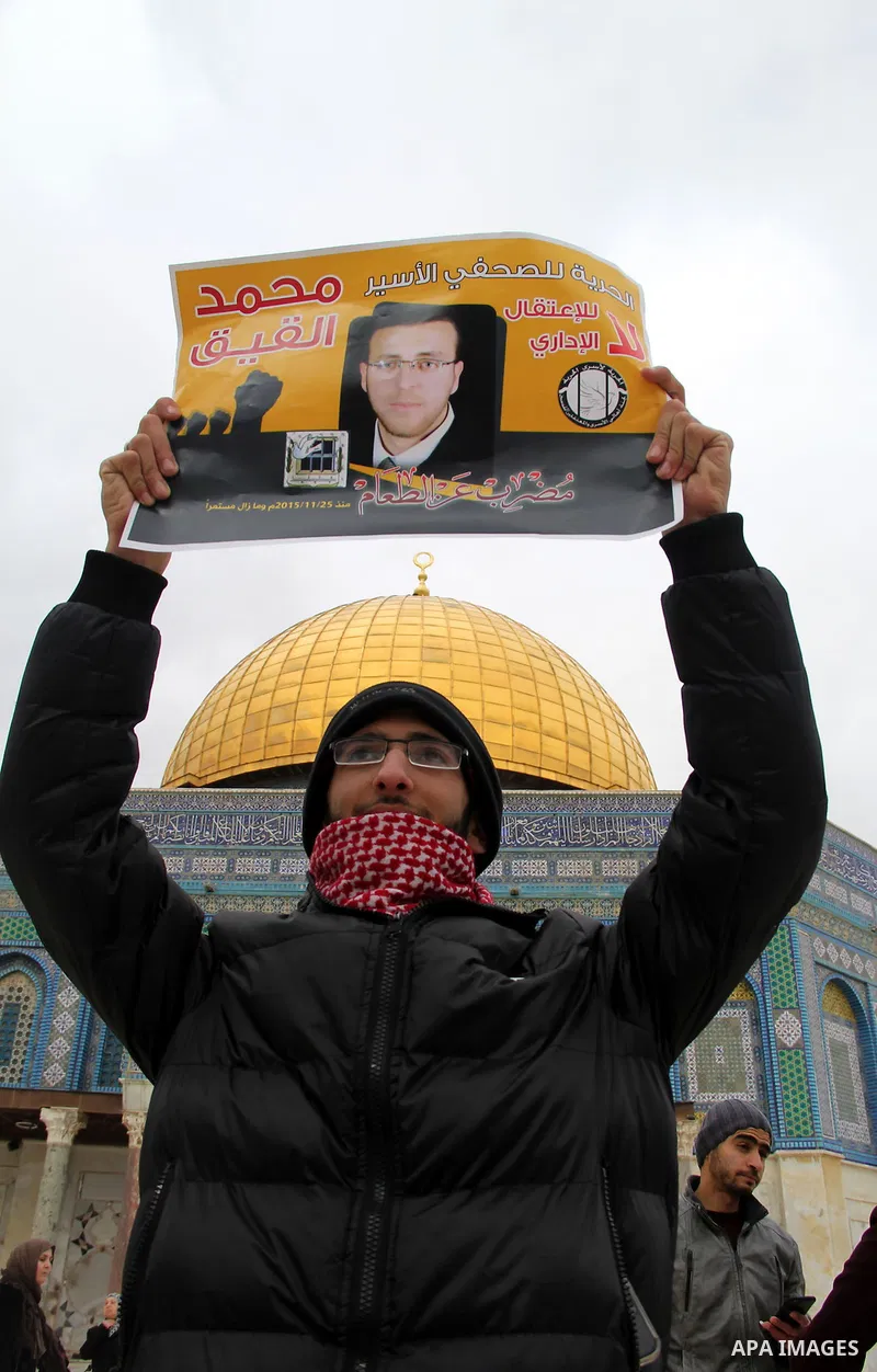 Palestinians hold posters bearing a portrait of Palestinian journalist Mohammed al-Qiq who is imprisoned in an Israeli jail during a protest in support of his hunger strike in front of Jerusalem's Dome of the Rock mosque...
