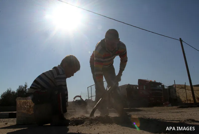 A Palestinian man collects the gravel which falling from trucks loaded with cement after it entered through the Kerem Shalom crossing in Rafah, to sell to customers, on January 31, 2016. Photo by Abed Rahim Khatib
