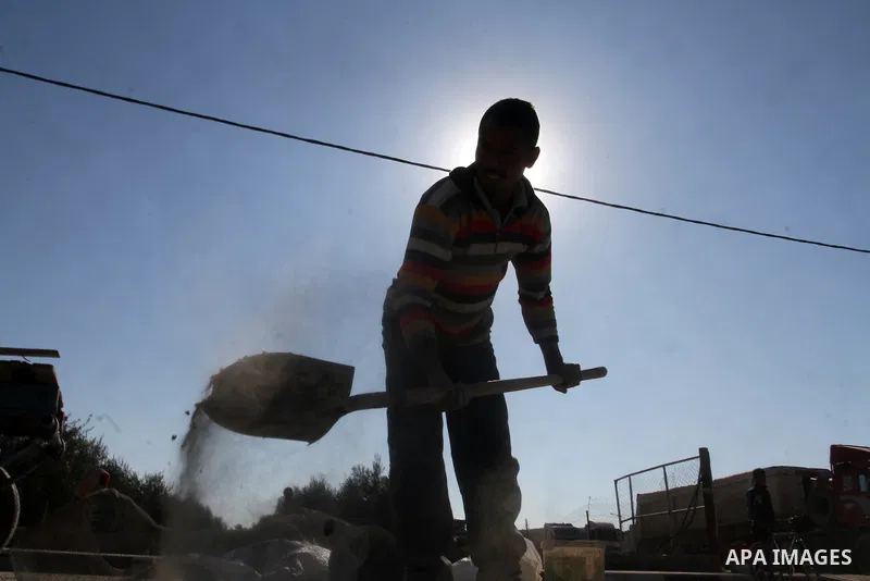 A Palestinian man collects the gravel which falling from trucks loaded with cement after it entered through the Kerem Shalom crossing in Rafah, to sell to customers, on January 31, 2016. Photo by Abed Rahim Khatib