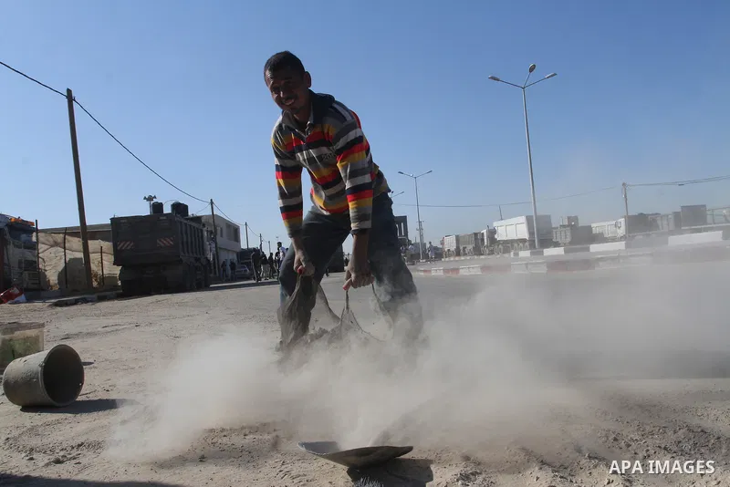 A Palestinian man collects the gravel which falling from trucks loaded with cement after it entered through the Kerem Shalom crossing in Rafah, to sell to customers, on January 31, 2016. Photo by Abed Rahim Khatib