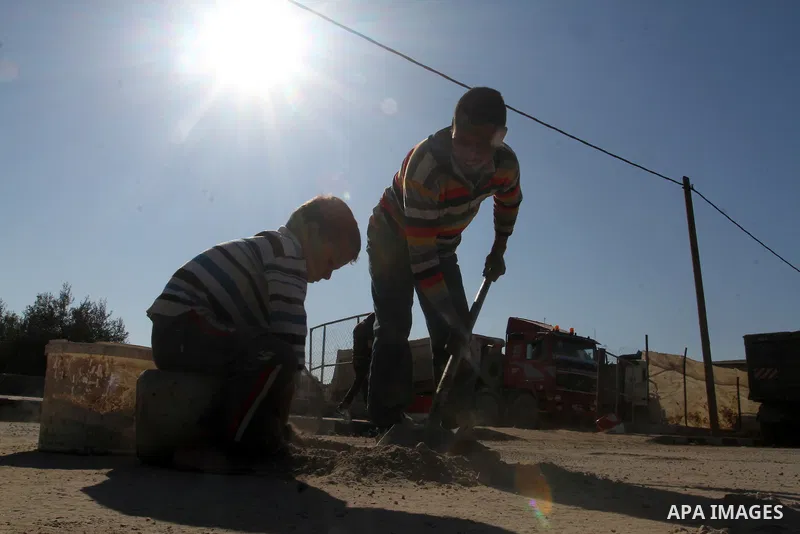 A Palestinian man collects the gravel which falling from trucks loaded with cement after it entered through the Kerem Shalom crossing in Rafah, to sell to customers, on January 31, 2016. Photo by Abed Rahim Khatib