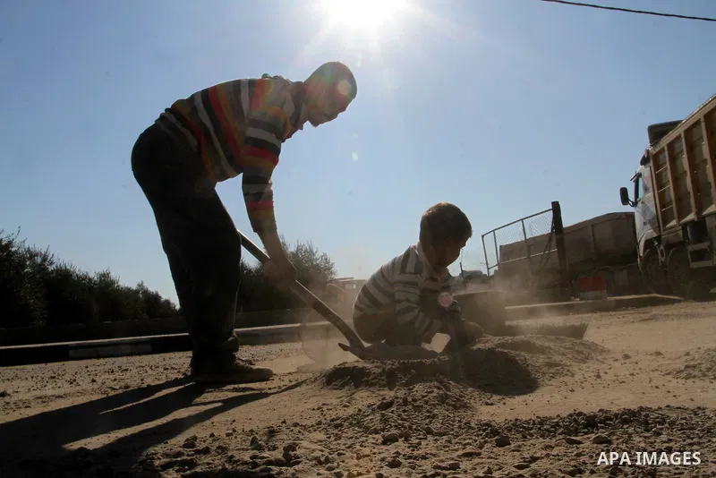 A Palestinian man collects the gravel which falling from trucks loaded with cement after it entered through the Kerem Shalom crossing in Rafah, to sell to customers, on January 31, 2016. Photo by Abed Rahim Khatib