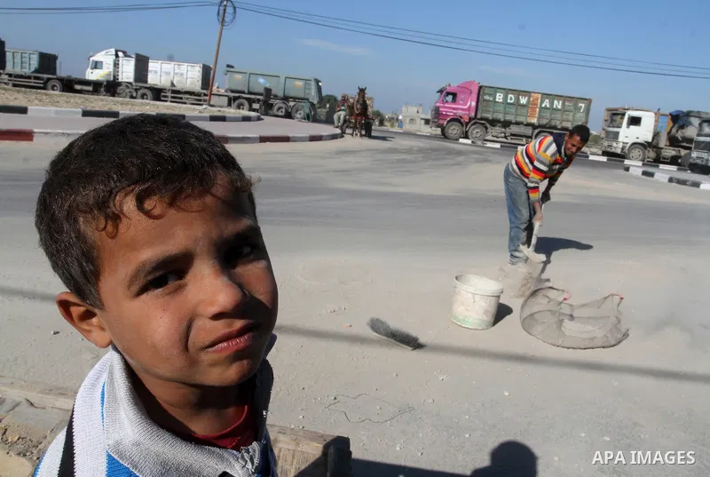 A Palestinian man collects the gravel which falling from trucks loaded with cement after it entered through the Kerem Shalom crossing in Rafah, to sell to customers, on January 31, 2016. Photo by Abed Rahim Khatib
