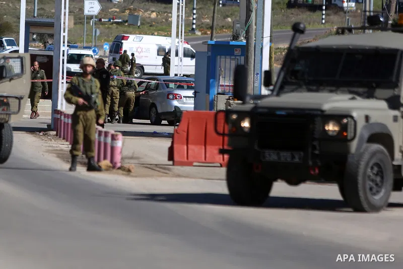 Israeli troops gather around the body of a dead Palestinian assailant at the scene of a shooting attack at an Israeli military checkpoint near the West Bank city of Ramallah January 31, 2016. Photo by Shadi Hatem