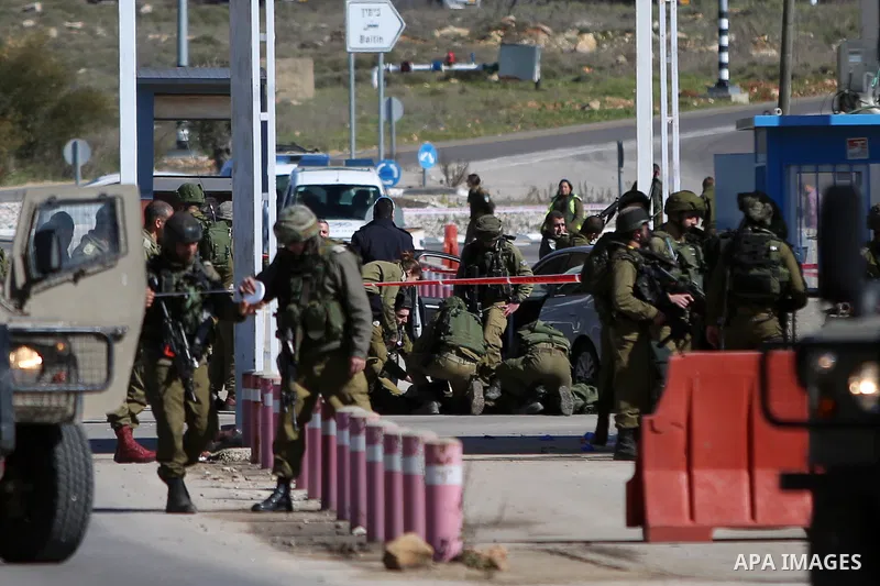 Israeli troops gather around the body of a dead Palestinian assailant at the scene of a shooting attack at an Israeli military checkpoint near the West Bank city of Ramallah January 31, 2016. Photo by Shadi Hatem