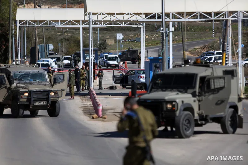 Israeli troops gather around the body of a dead Palestinian assailant at the scene of a shooting attack at an Israeli military checkpoint near the West Bank city of Ramallah January 31, 2016. Photo by Shadi Hatem