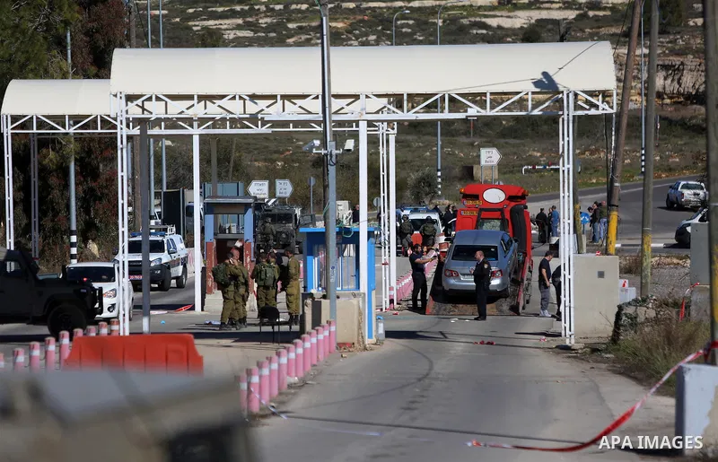 Israeli troops gather around the body of a dead Palestinian assailant at the scene of a shooting attack at an Israeli military checkpoint near the West Bank city of Ramallah January 31, 2016. Photo by Shadi Hatem