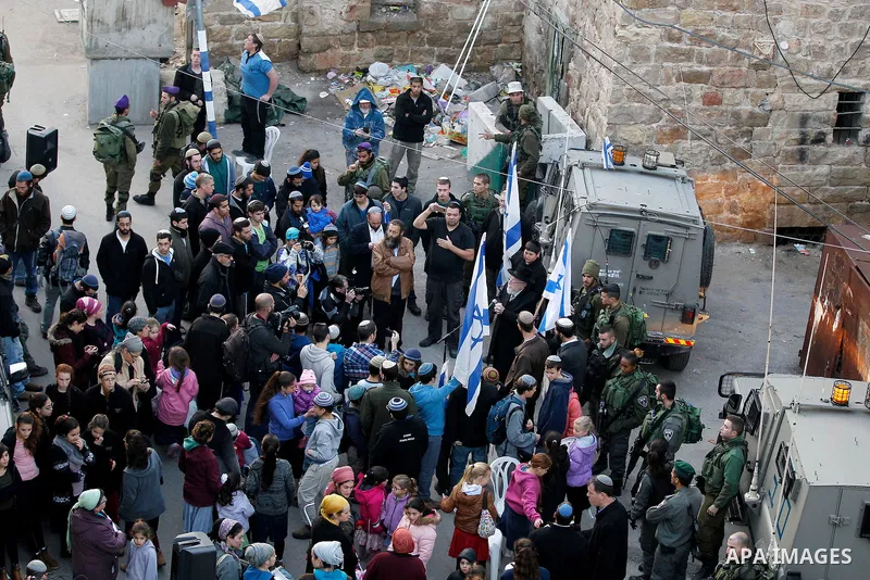 Jewish settlers escort of Israeli border police gather outside two Palestinian homes which evacuated from it by Israeli security forces on Jan. 22 in the heart of the West Bank city of Hebron on January 31, 2016. The bui...