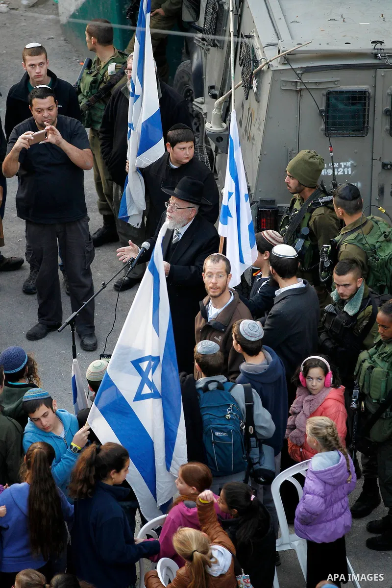 Jewish settlers escort of Israeli border police gather outside two Palestinian homes which evacuated from it by Israeli security forces on Jan. 22 in the heart of the West Bank city of Hebron on January 31, 2016. The bui...