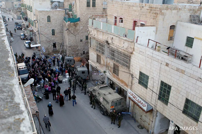 Jewish settlers escort of Israeli border police gather outside two Palestinian homes which evacuated from it by Israeli security forces on Jan. 22 in the heart of the West Bank city of Hebron on January 31, 2016. The bui...