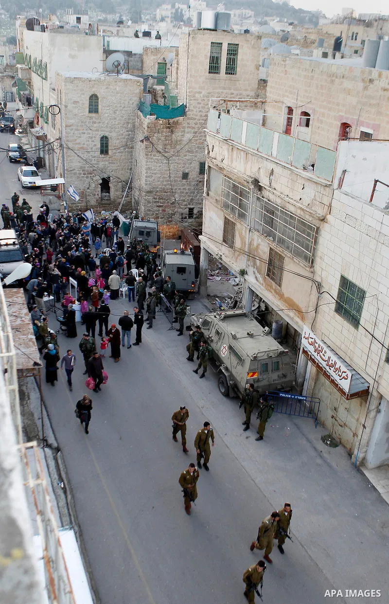 Jewish settlers escort of Israeli border police gather outside two Palestinian homes which evacuated from it by Israeli security forces on Jan. 22 in the heart of the West Bank city of Hebron on January 31, 2016. The bui...