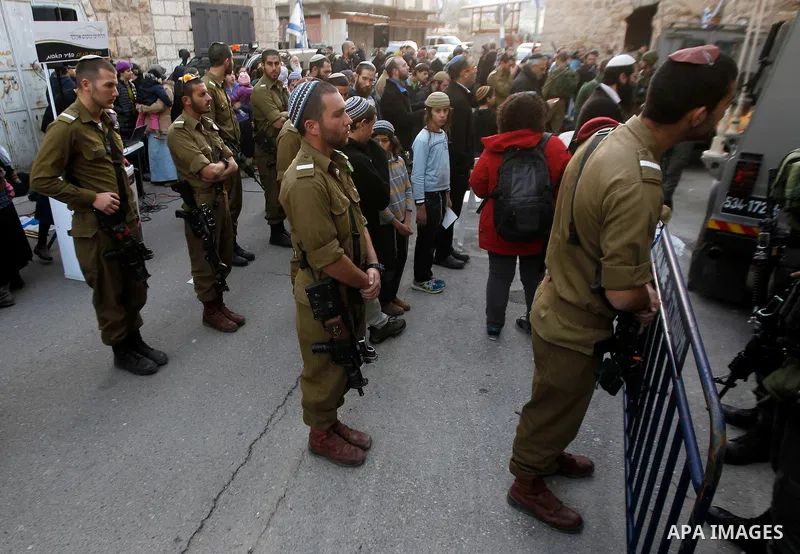 Jewish settlers escort of Israeli border police gather outside two Palestinian homes which evacuated from it by Israeli security forces on Jan. 22 in the heart of the West Bank city of Hebron on January 31, 2016. The bui...