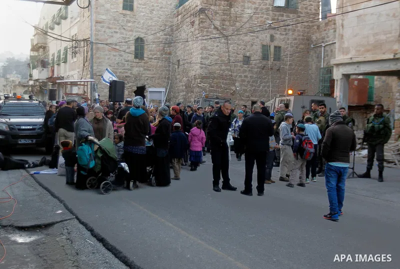 Jewish settlers escort of Israeli border police gather outside two Palestinian homes which evacuated from it by Israeli security forces on Jan. 22 in the heart of the West Bank city of Hebron on January 31, 2016. The bui...