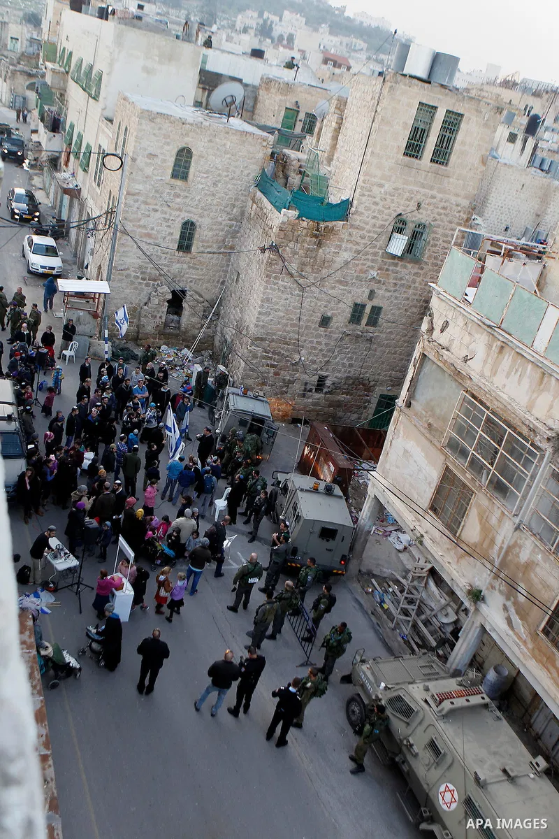 Jewish settlers escort of Israeli border police gather outside two Palestinian homes which evacuated from it by Israeli security forces on Jan. 22 in the heart of the West Bank city of Hebron on January 31, 2016. The bui...