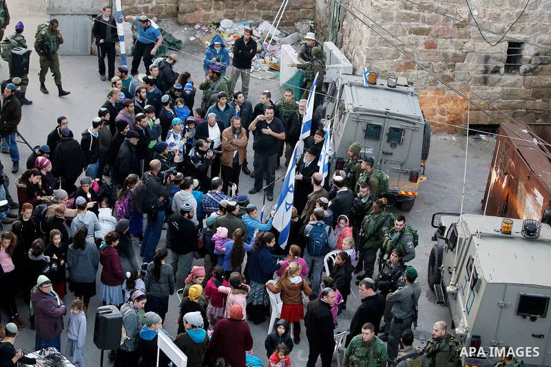 Jewish settlers escort of Israeli border police gather outside two Palestinian homes which evacuated from it by Israeli security forces on Jan. 22 in the heart of the West Bank city of Hebron on January 31, 2016. The bui...