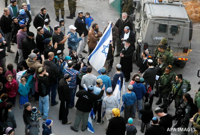 Jewish settlers escort of Israeli border police gather outside two Palestinian homes which evacuated from it by Israeli security forces on Jan. 22 in the heart of the West Bank city of Hebron on January 31, 2016. The bui...