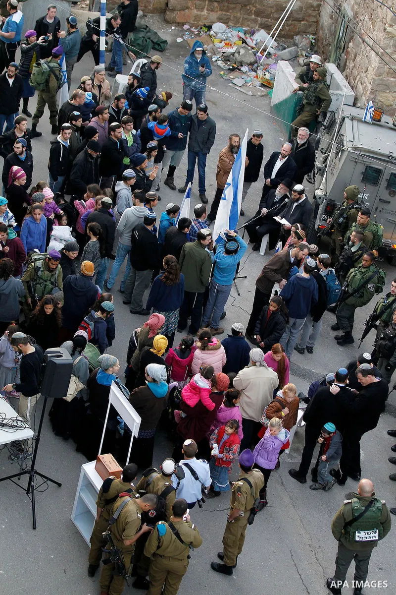 Jewish settlers escort of Israeli border police gather outside two Palestinian homes which evacuated from it by Israeli security forces on Jan. 22 in the heart of the West Bank city of Hebron on January 31, 2016. The bui...