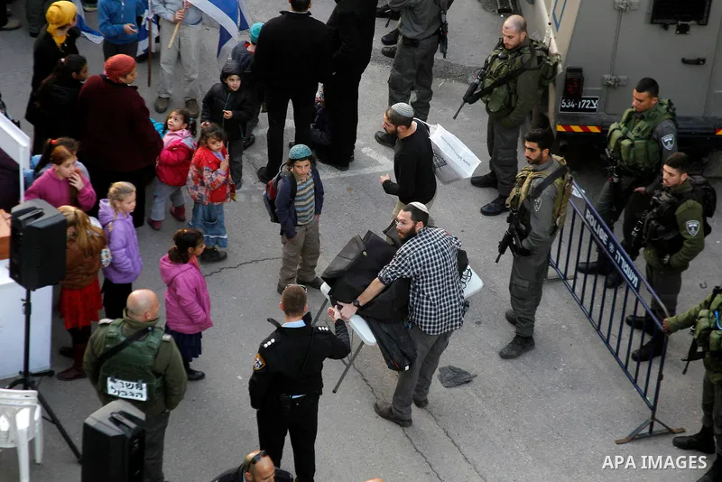 Jewish settlers escort of Israeli border police gather outside two Palestinian homes which evacuated from it by Israeli security forces on Jan. 22 in the heart of the West Bank city of Hebron on January 31, 2016. The bui...
