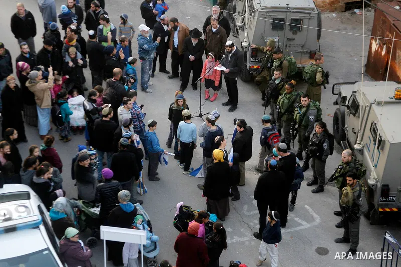 Jewish settlers escort of Israeli border police gather outside two Palestinian homes which evacuated from it by Israeli security forces on Jan. 22 in the heart of the West Bank city of Hebron on January 31, 2016. The bui...
