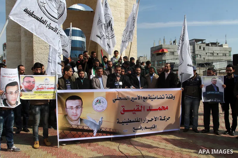 Palestinians hold posters bearing a portrait of Palestinian journalist Mohammed al-Qiq who is imprisoned in an Israeli jail during a protest in support of his hunger strike in rafah in the southern Gaza strip, on Feb. 01...