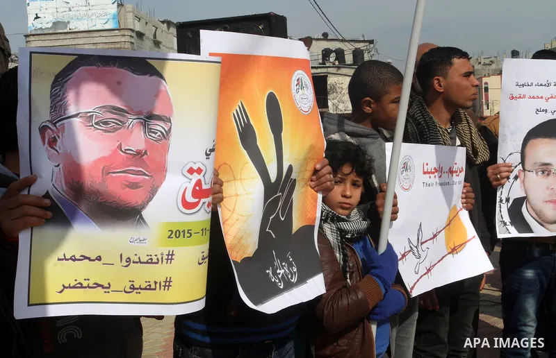 Palestinians hold posters bearing a portrait of Palestinian journalist Mohammed al-Qiq who is imprisoned in an Israeli jail during a protest in support of his hunger strike in rafah in the southern Gaza strip, on Feb. 01...