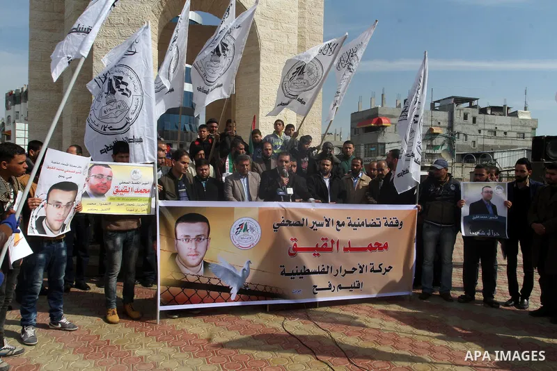 Palestinians hold posters bearing a portrait of Palestinian journalist Mohammed al-Qiq who is imprisoned in an Israeli jail during a protest in support of his hunger strike in rafah in the southern Gaza strip, on Feb. 01...