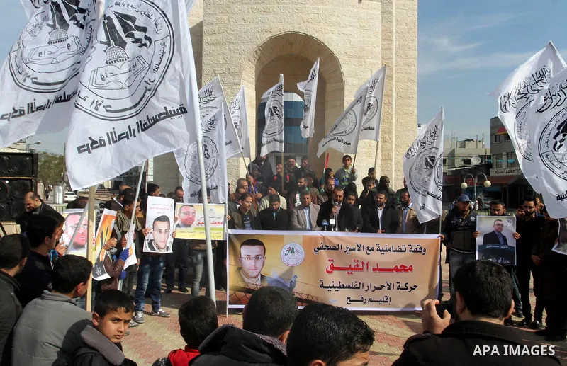 Palestinians hold posters bearing a portrait of Palestinian journalist Mohammed al-Qiq who is imprisoned in an Israeli jail during a protest in support of his hunger strike in rafah in the southern Gaza strip, on Feb. 01...