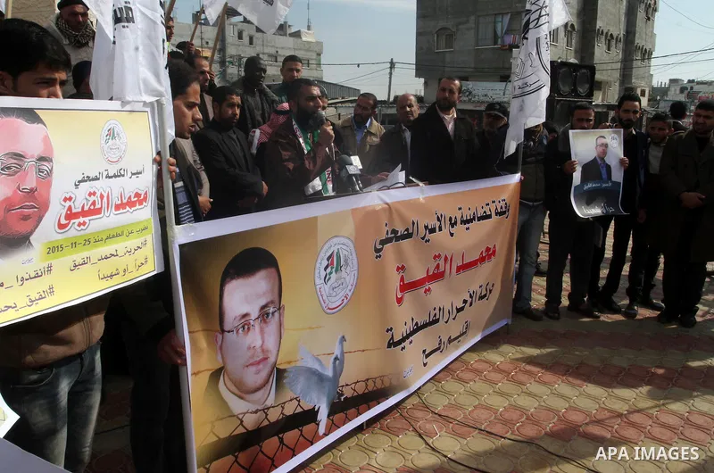 Palestinians hold posters bearing a portrait of Palestinian journalist Mohammed al-Qiq who is imprisoned in an Israeli jail during a protest in support of his hunger strike in rafah in the southern Gaza strip, on Feb. 01...
