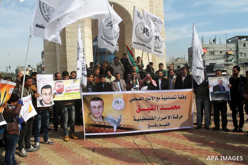 Palestinians hold posters bearing a portrait of Palestinian journalist Mohammed al-Qiq who is imprisoned in an Israeli jail during a protest in support of his hunger strike in rafah in the southern Gaza strip, on Feb. 01...