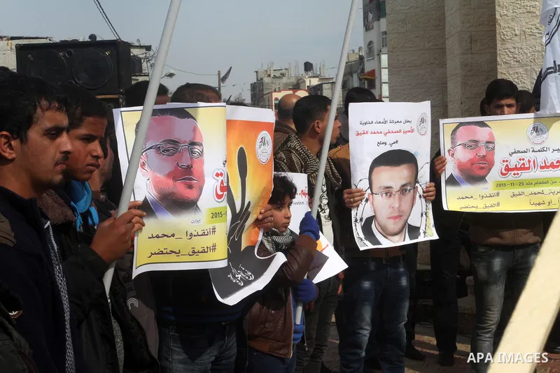 Palestinians hold posters bearing a portrait of Palestinian journalist Mohammed al-Qiq who is imprisoned in an Israeli jail during a protest in support of his hunger strike in rafah in the southern Gaza strip, on Feb. 01...