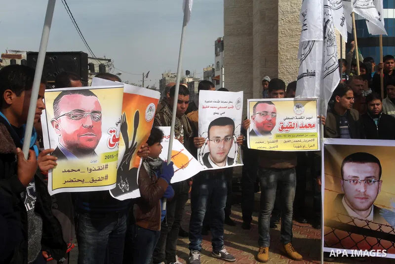 Palestinians hold posters bearing a portrait of Palestinian journalist Mohammed al-Qiq who is imprisoned in an Israeli jail during a protest in support of his hunger strike in rafah in the southern Gaza strip, on Feb. 01...