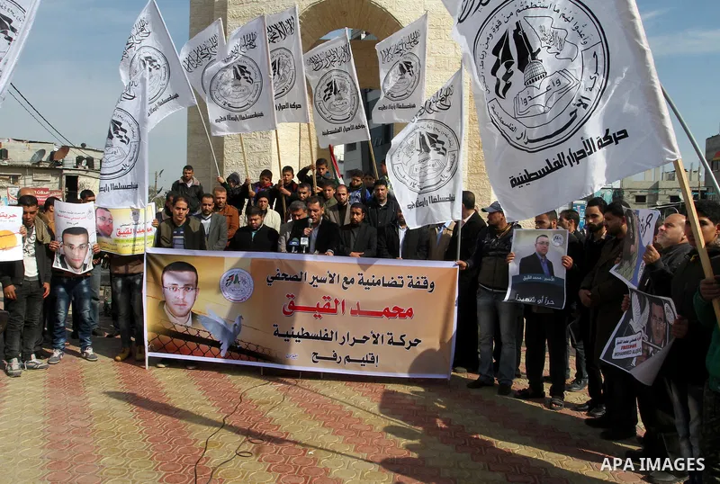 Palestinians hold posters bearing a portrait of Palestinian journalist Mohammed al-Qiq who is imprisoned in an Israeli jail during a protest in support of his hunger strike in rafah in the southern Gaza strip, on Feb. 01...
