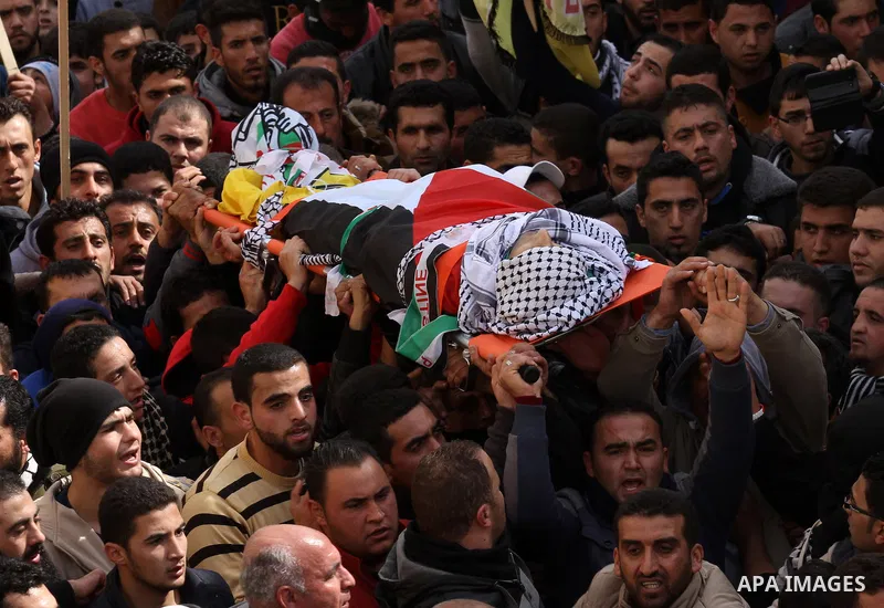 Mourners carry the body of Palestinian gunman Amjad Abu Omar, whom the Israeli army said was shot dead by soldiers after he wounded three Israelis on Sunday, during his funeral in the West Bank village of Jamain near Nab...
