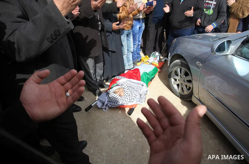 Palestinians pray in front of the body of Palestinian gunman Amjad Abu Omar, whom the Israeli army said was shot dead by soldiers after he wounded three Israelis on Sunday, during his funeral in the West Bank village of...
