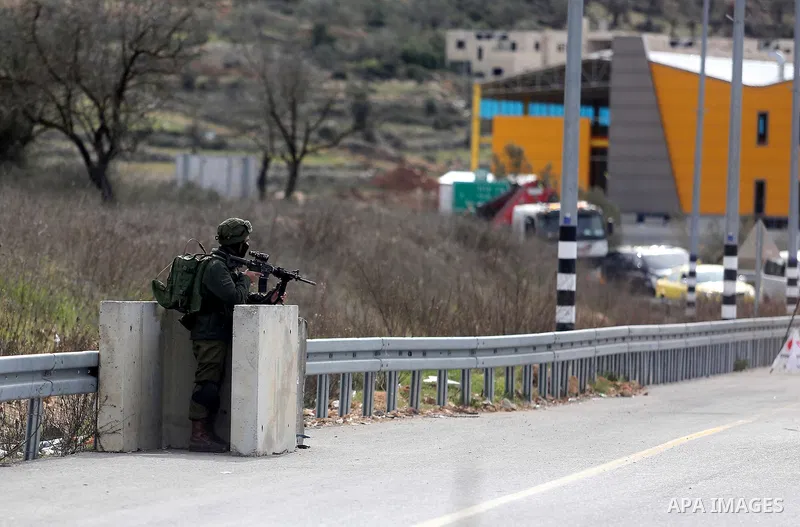An Israeli soldier stands guard as he checks Palestinians' vehicles on their way out of the West Bank village of Ein Sinya, northern Ramallah on February 1, 2016. Israel blocked non-residents from Ramallah after a checkp...