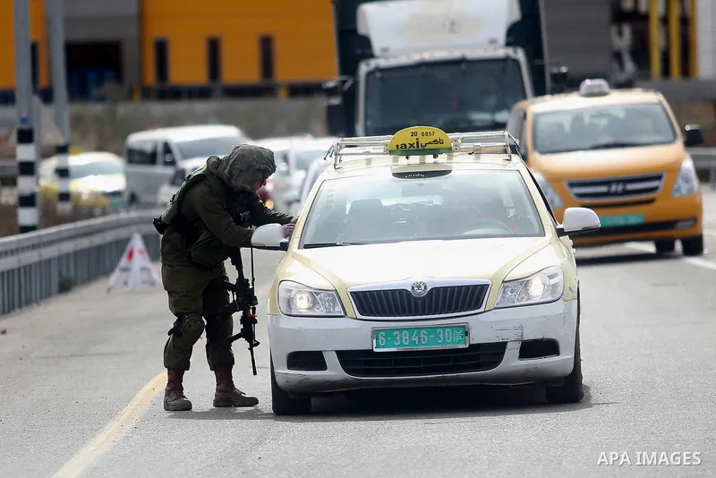 An Israeli soldier checks the documents of the Palestinian passengers of a taxi on their way out of the West Bank village of Ein Sinya, northern Ramallah on February 1, 2016. Israel blocked non-residents from Ramallah af...