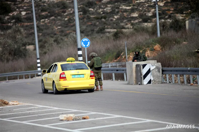 An Israeli soldier checks the documents of the Palestinian passengers of a taxi on their way out of the West Bank village of Ein Sinya, northern Ramallah on February 1, 2016. Israel blocked non-residents from Ramallah af...